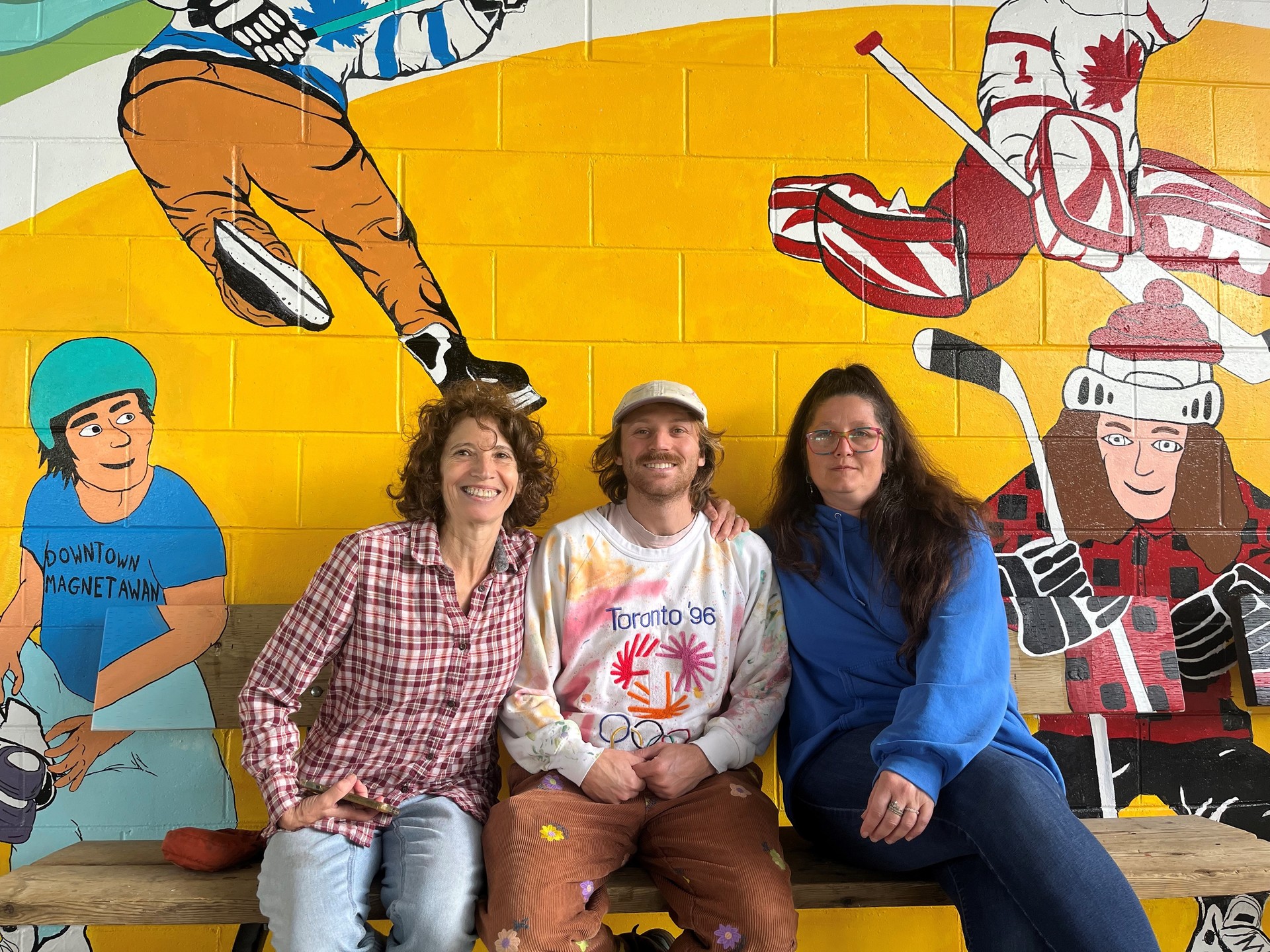artists sitting in front of their mural