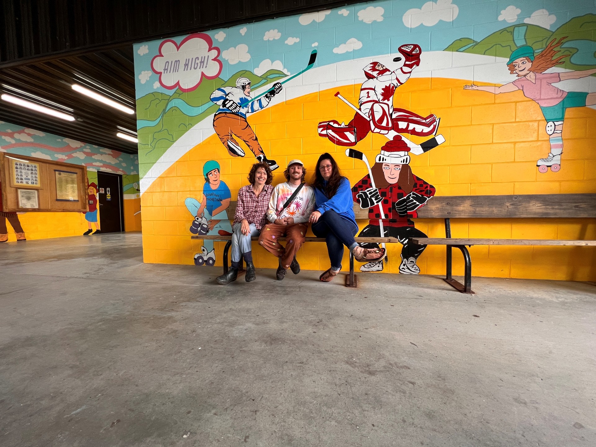 artists sitting in front of their mural