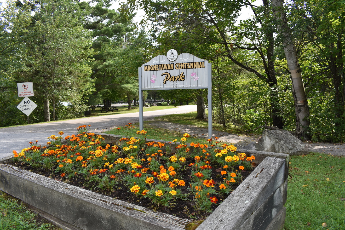 Magnetawan Centennial Park Entry Sign with flower bed and trees