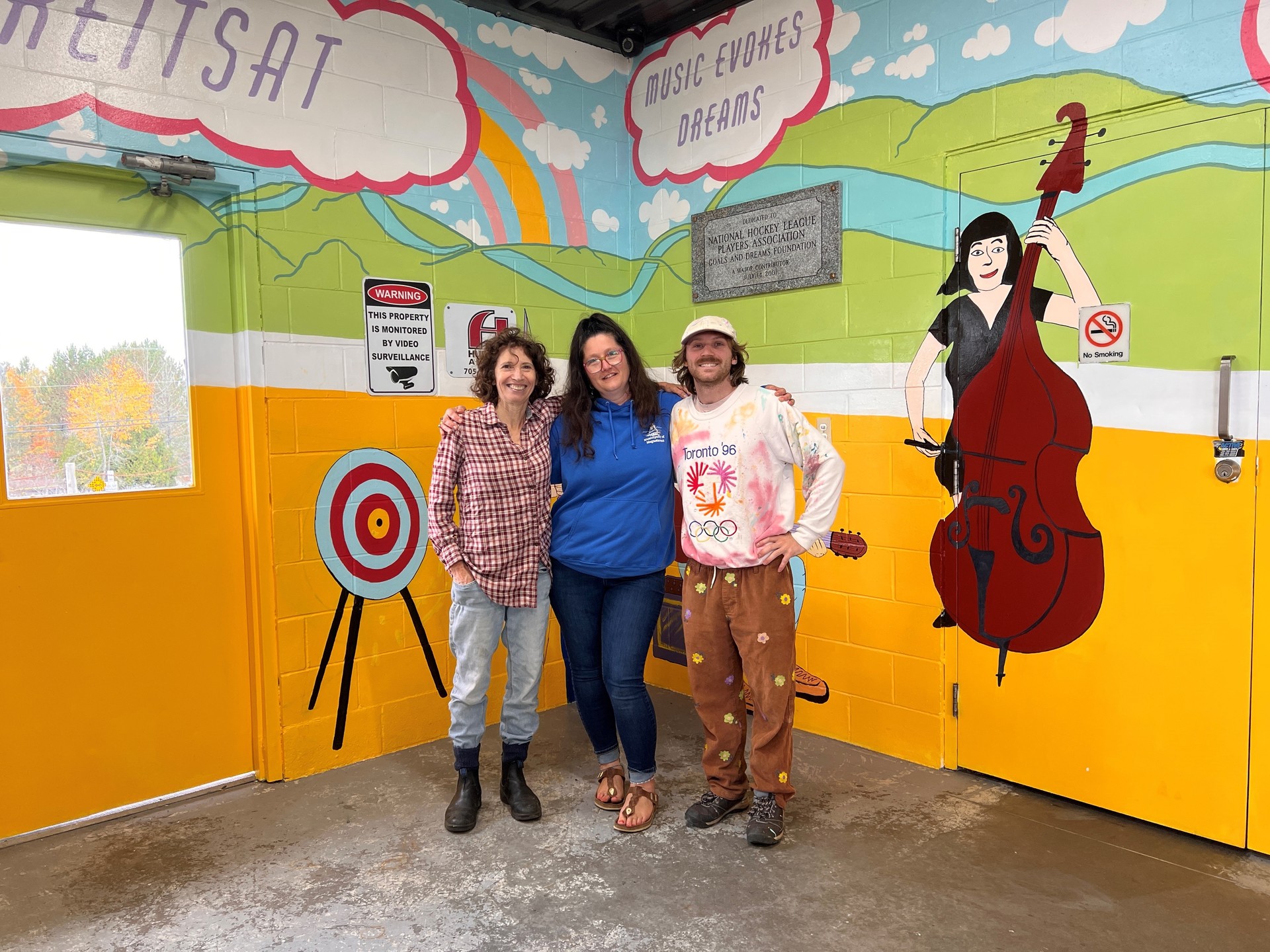 artists standing in front of their mural